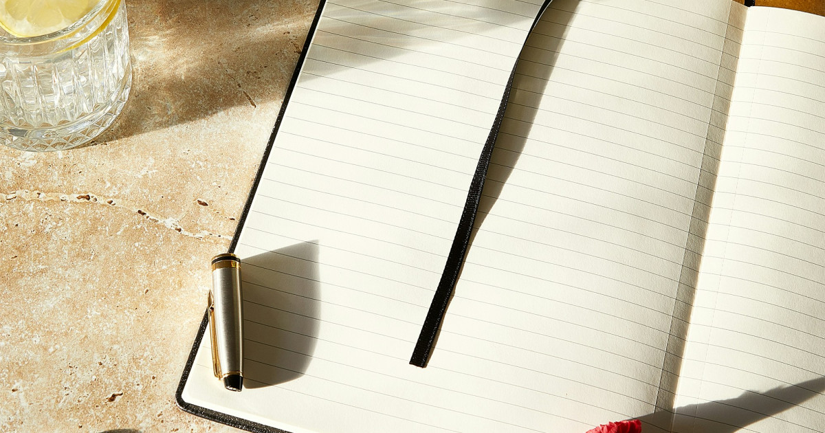 Open notebook with pen on marble surface